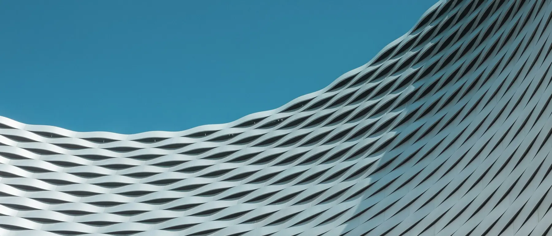 The rippled white facade of a modern building against the sky