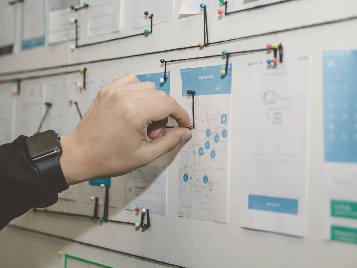 A hand pinning a card onto a wall covered in process diagrams